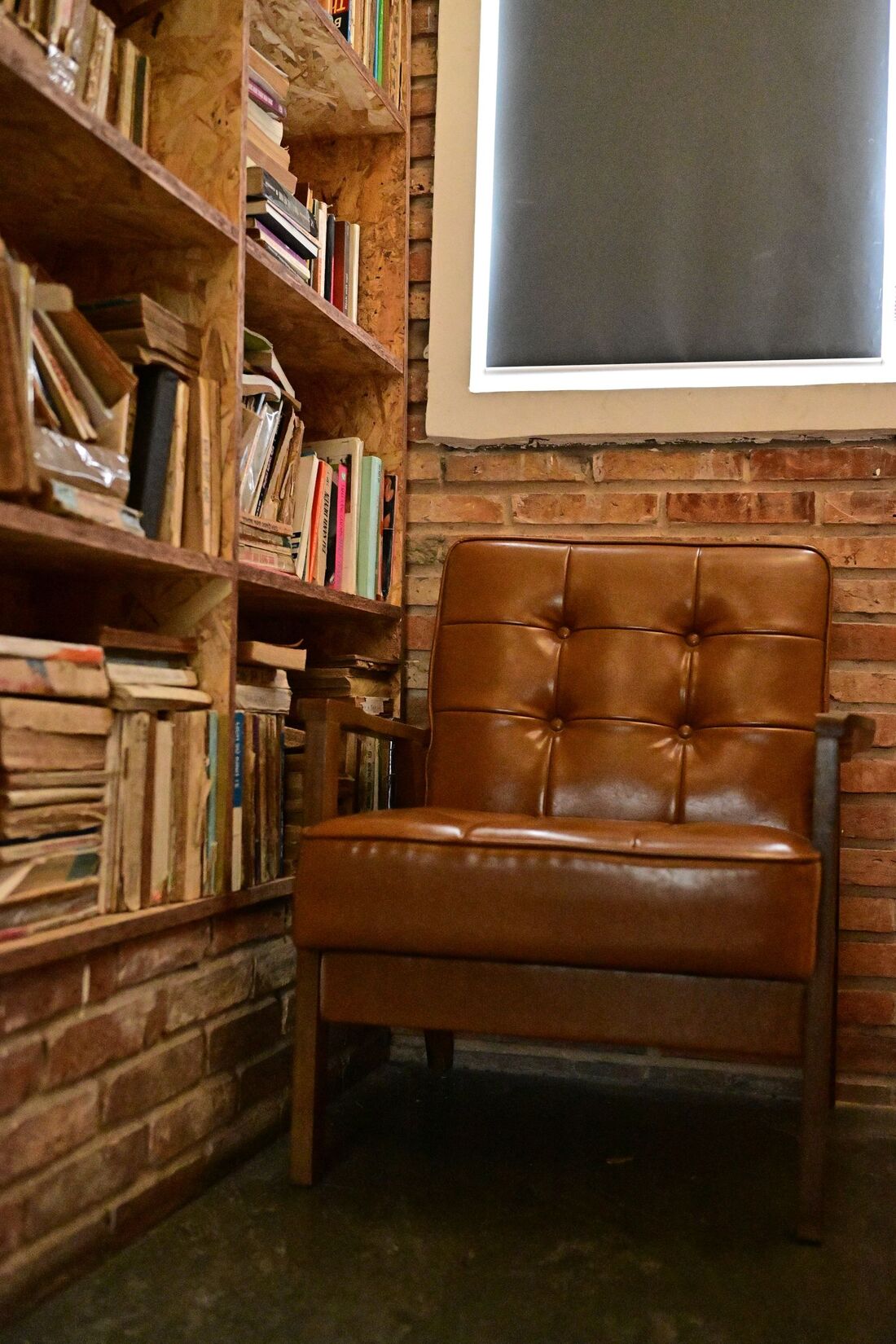 A leather armchair and a lamp beside a wooden bookshelf